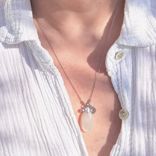 Collier en pierre de lune posé sur un support en bois naturel.