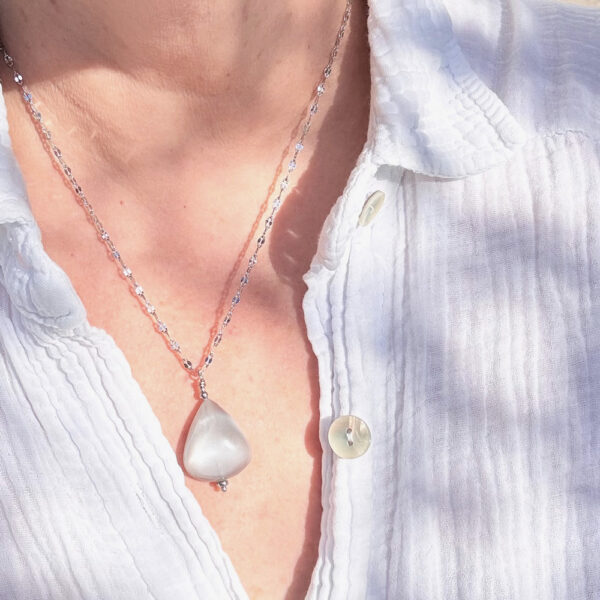 Zoom sur un collier en pierre de lune artisanale, reflets irisés.