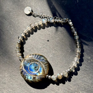 Bracelet en labradorite naturelle avec œil protecteur en gros plan, mettant en valeur les reflets bleutés et ses vertus de protection énergétique.