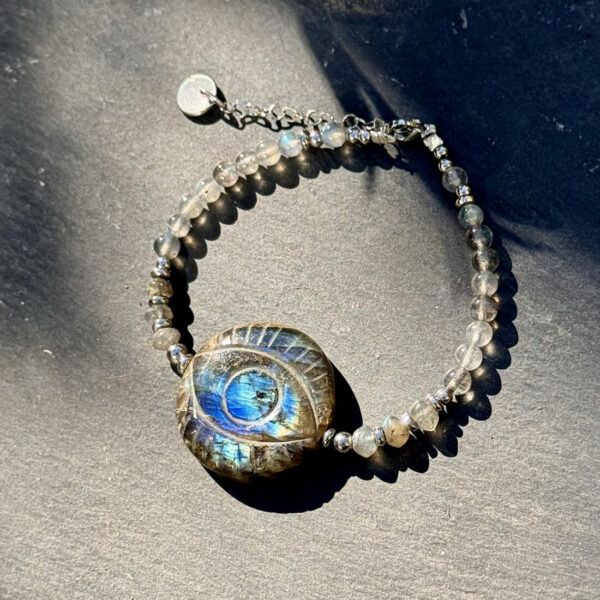 Vue rapprochée du bracelet en labradorite avec œil protecteur, révélant les reflets bleus caractéristiques de cette pierre de protection.