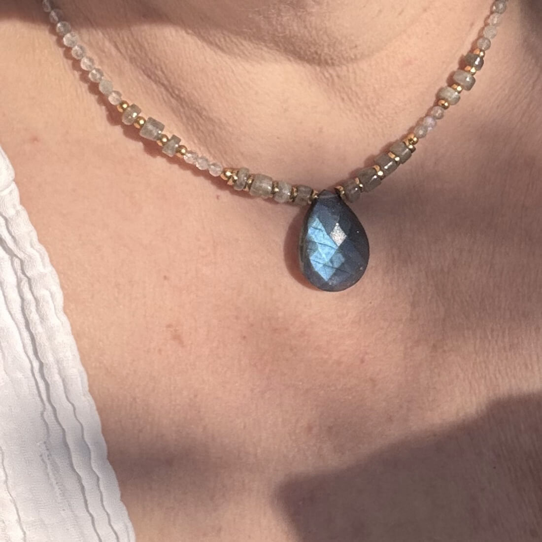 Cabochon de labradorite porté sur le décolleté, bijou en pierres naturelles stimulant la confiance en soi et la connexion à son intuition.