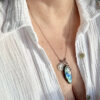 collier-labradorite-medaille-marie-enfant-jesus-detail-pierre Gros plan sur un collier en pierre naturelle labradorite avec médaille Marie et enfant Jésus, mettant en valeur les reflets protecteurs de la pierre, idéal pour renforcer la confiance, l’intuition et les énergies positives.