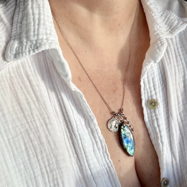 collier-labradorite-medaille-marie-enfant-jesus-detail-pierre Gros plan sur un collier en pierre naturelle labradorite avec médaille Marie et enfant Jésus, mettant en valeur les reflets protecteurs de la pierre, idéal pour renforcer la confiance, l’intuition et les énergies positives.