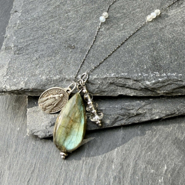 collier-labradorite-medaille-miraculeuse-detail-pierre Gros plan sur un collier en pierre naturelle labradorite avec médaille miraculeuse, mettant en valeur les reflets protecteurs de la pierre, parfait pour renforcer l’équilibre intérieur et accompagner une démarche de bien-être au quotidien.