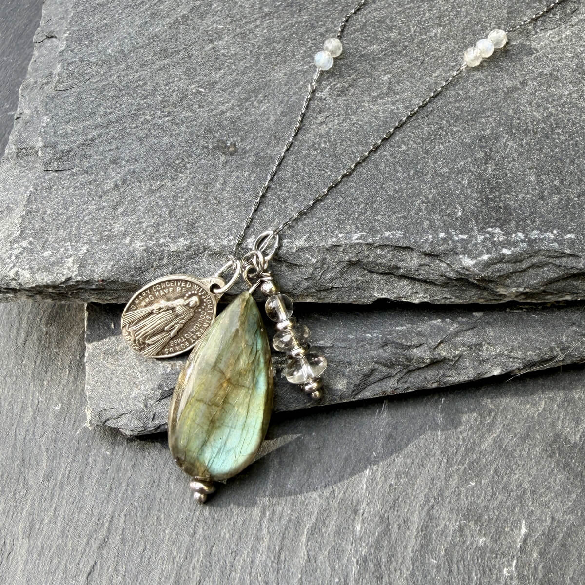 Gros plan sur un collier en pierre naturelle labradorite avec médaille miraculeuse, mettant en valeur les reflets protecteurs de la pierre, parfait pour renforcer l’équilibre intérieur et accompagner une démarche de bien-être au quotidien.