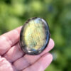 galet-labradorite-multicolore-face-fond-bleu-soleil-ombre Face principale d'un galet en labradorite naturelle multicolore posé sur fond bleu en plein soleil. Les nuances jaune, vert, bleu et turquoise de la labradorescence se mélangent de façon spectaculaire. Pierre de lithothérapie pour accompagner les transitions de vie. Belle de Lune Bijoux.